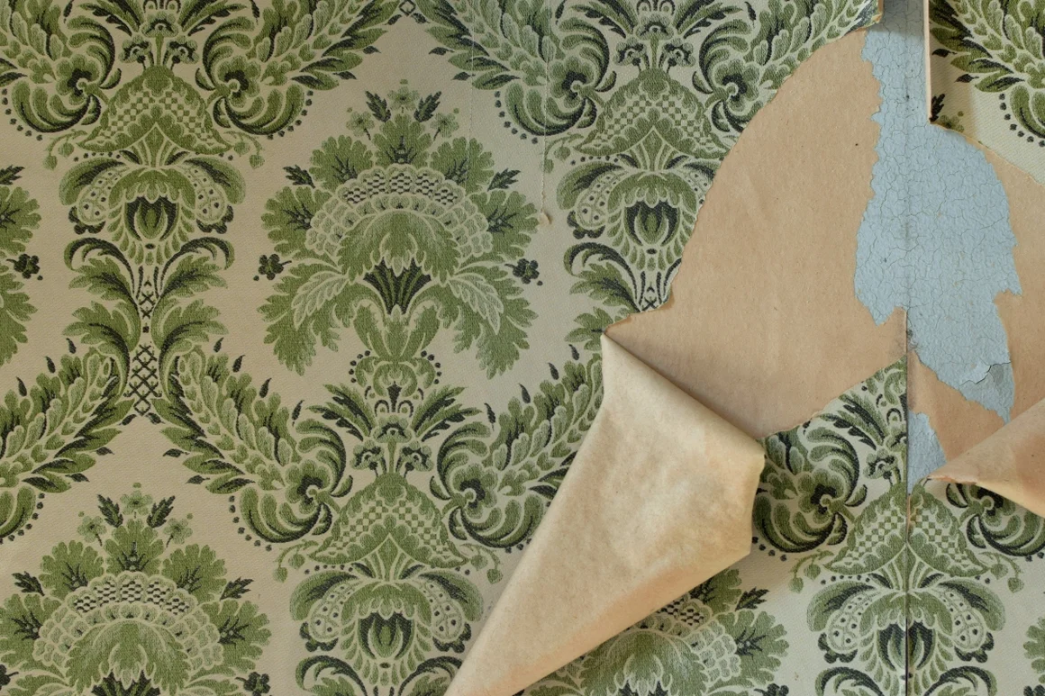 Alte, grüne Mustertapete löst sich von der Wand.